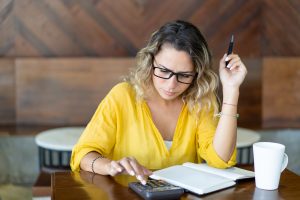 Woman using a calculator and pen and paper to run calculations